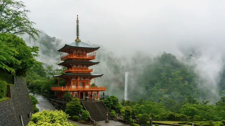 Red pagoda in misty green mountains with a waterfall